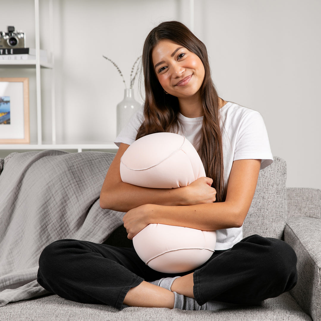 Woman sitting on a couch holding a white ball in a home setting